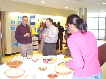 Students and Professors Sawin, Kubasik and Harriott gather around the refreshments